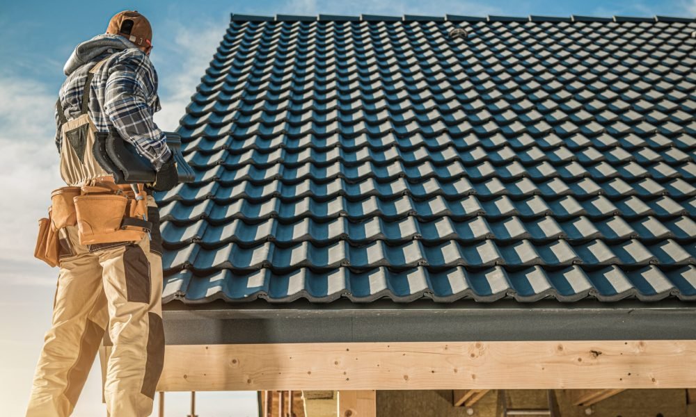 Tile Roofing Worker and the House Construction. Scaffolding on the Home Side. Industrial Theme.