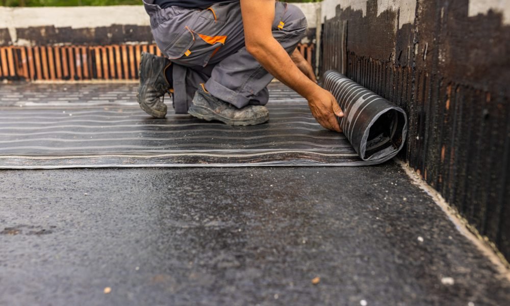 Worker laying the vapor barrier for the roof, bituminous membrane to be welded with flame